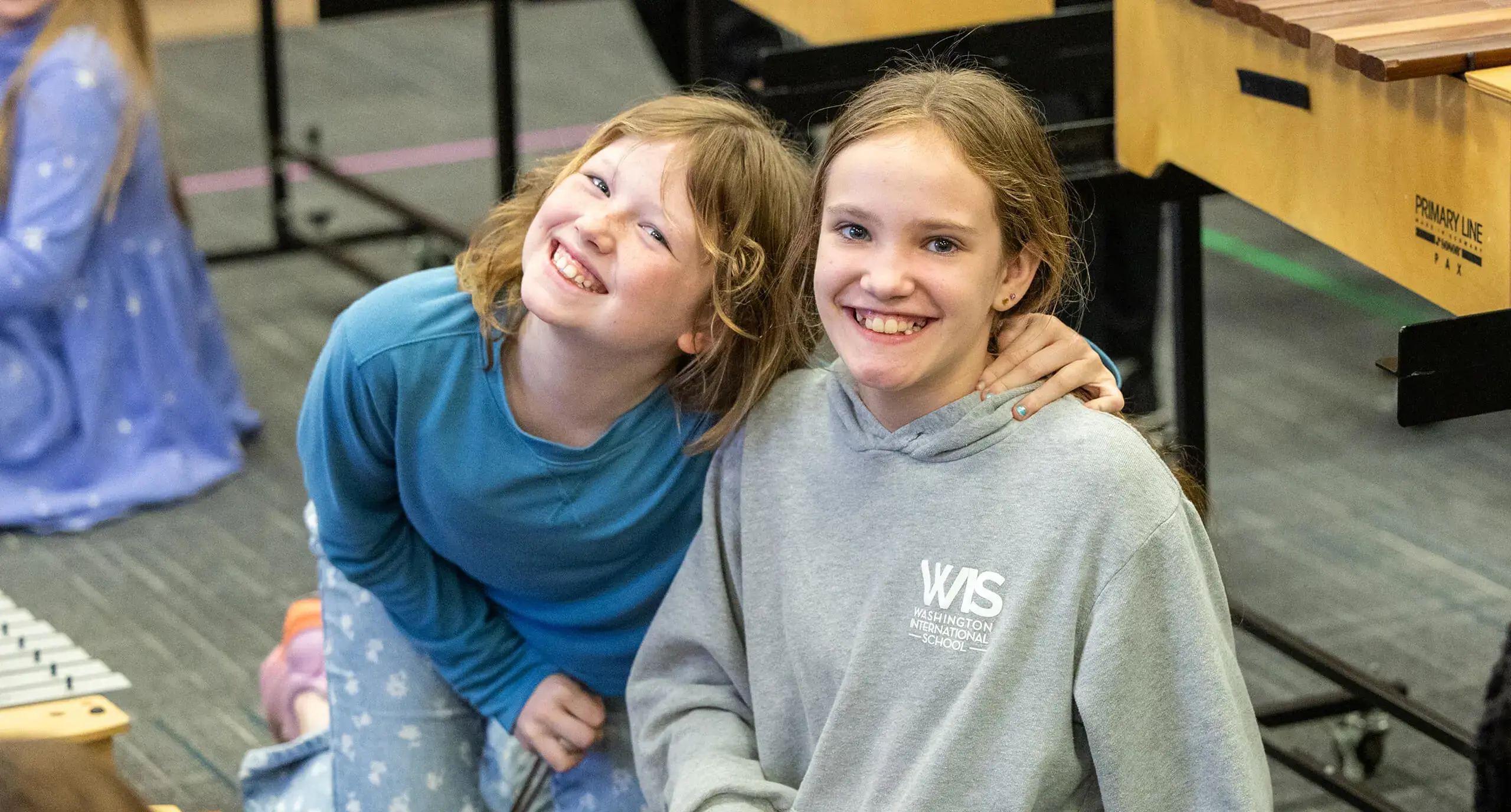 girls hugging while holding xylophone mallets