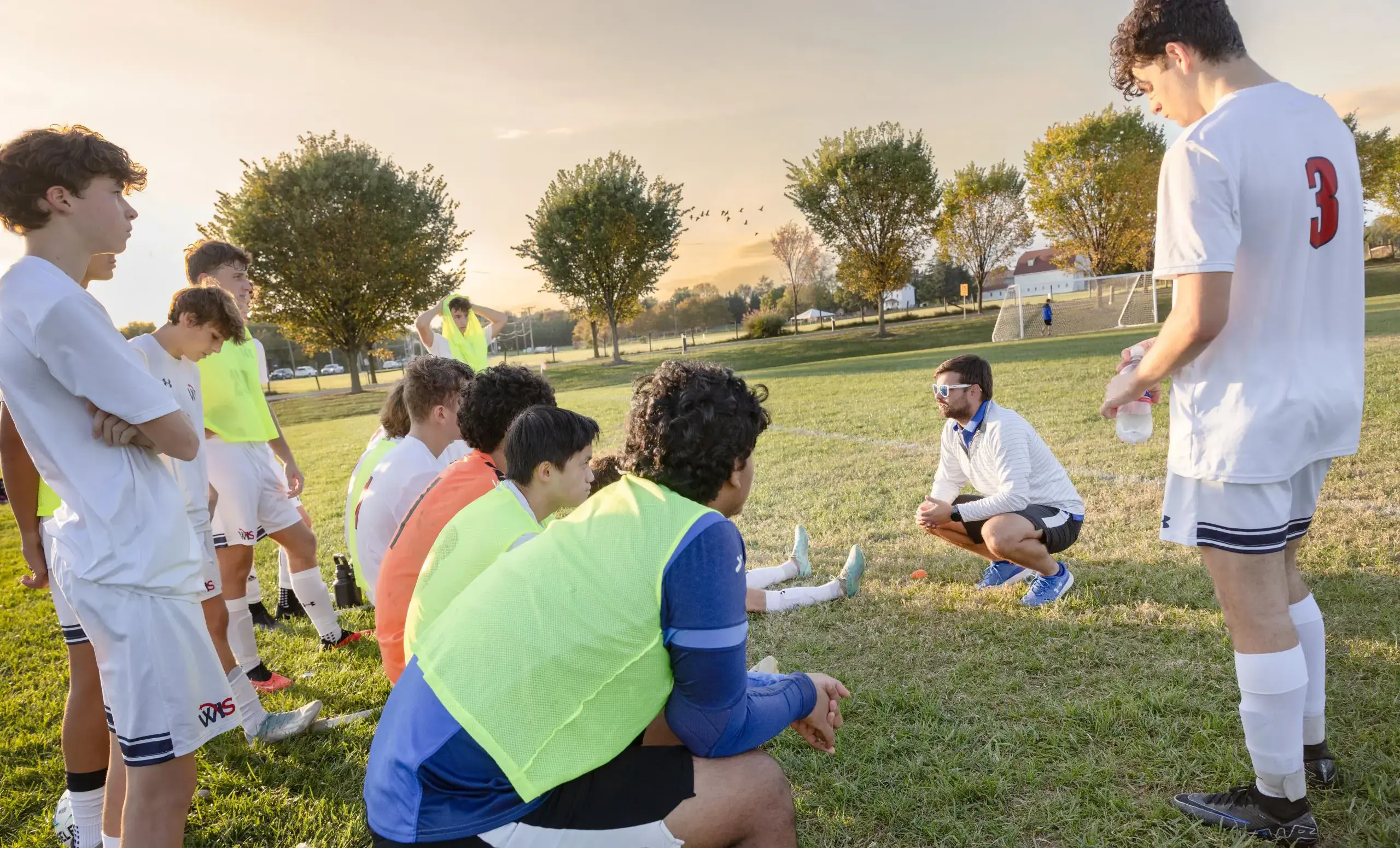 Coach talking to soccer team members on a field