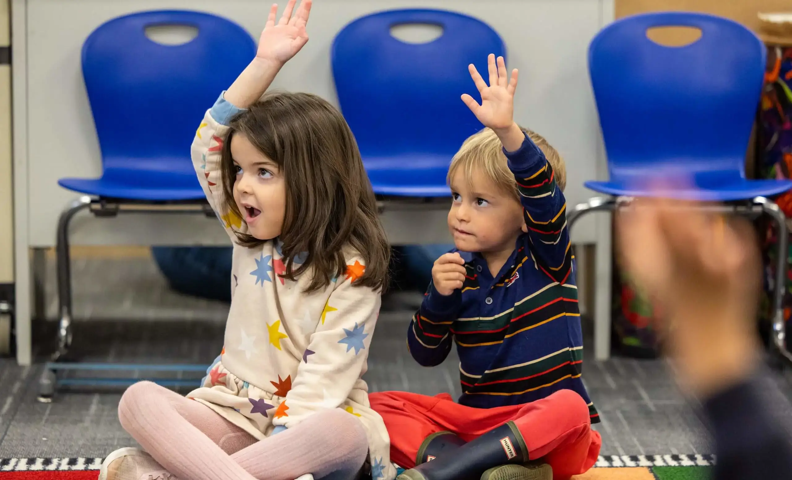 Kids raising their hands in class