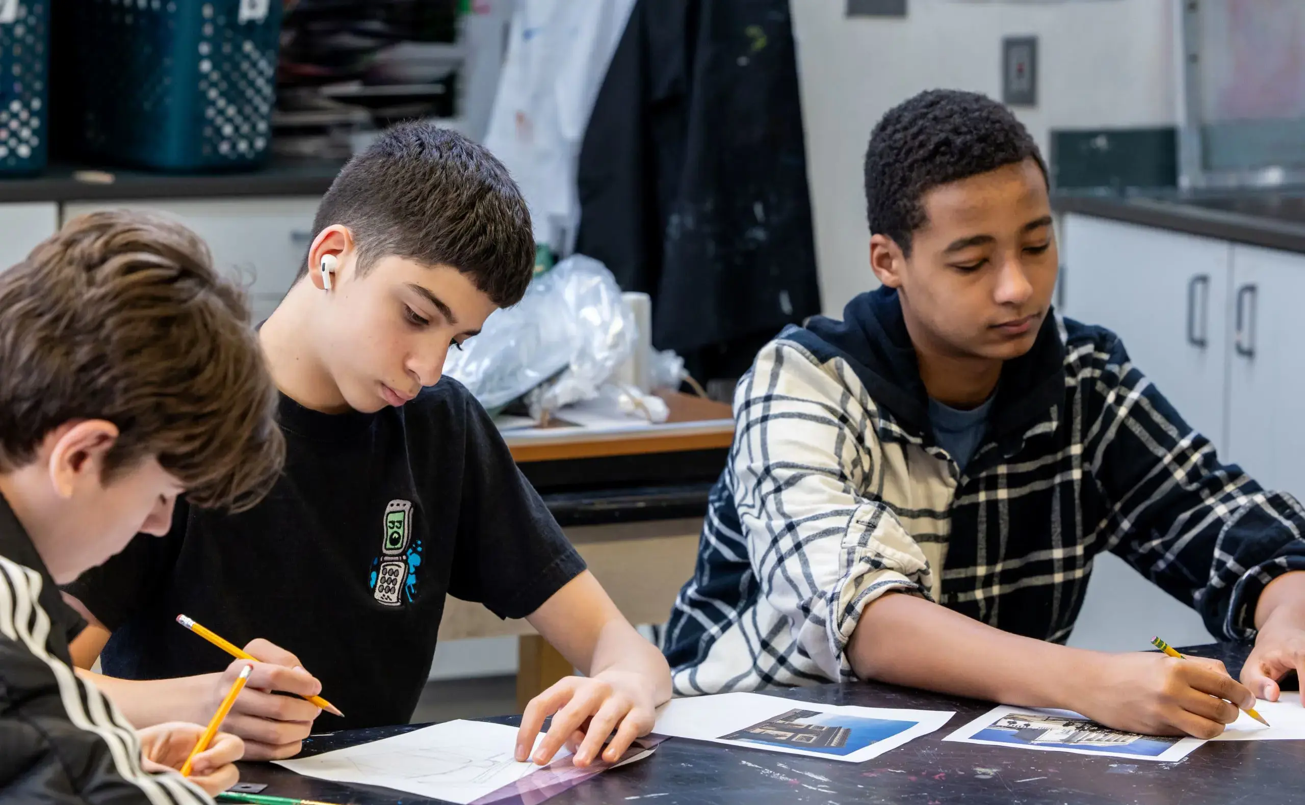 Three students drawing in art class