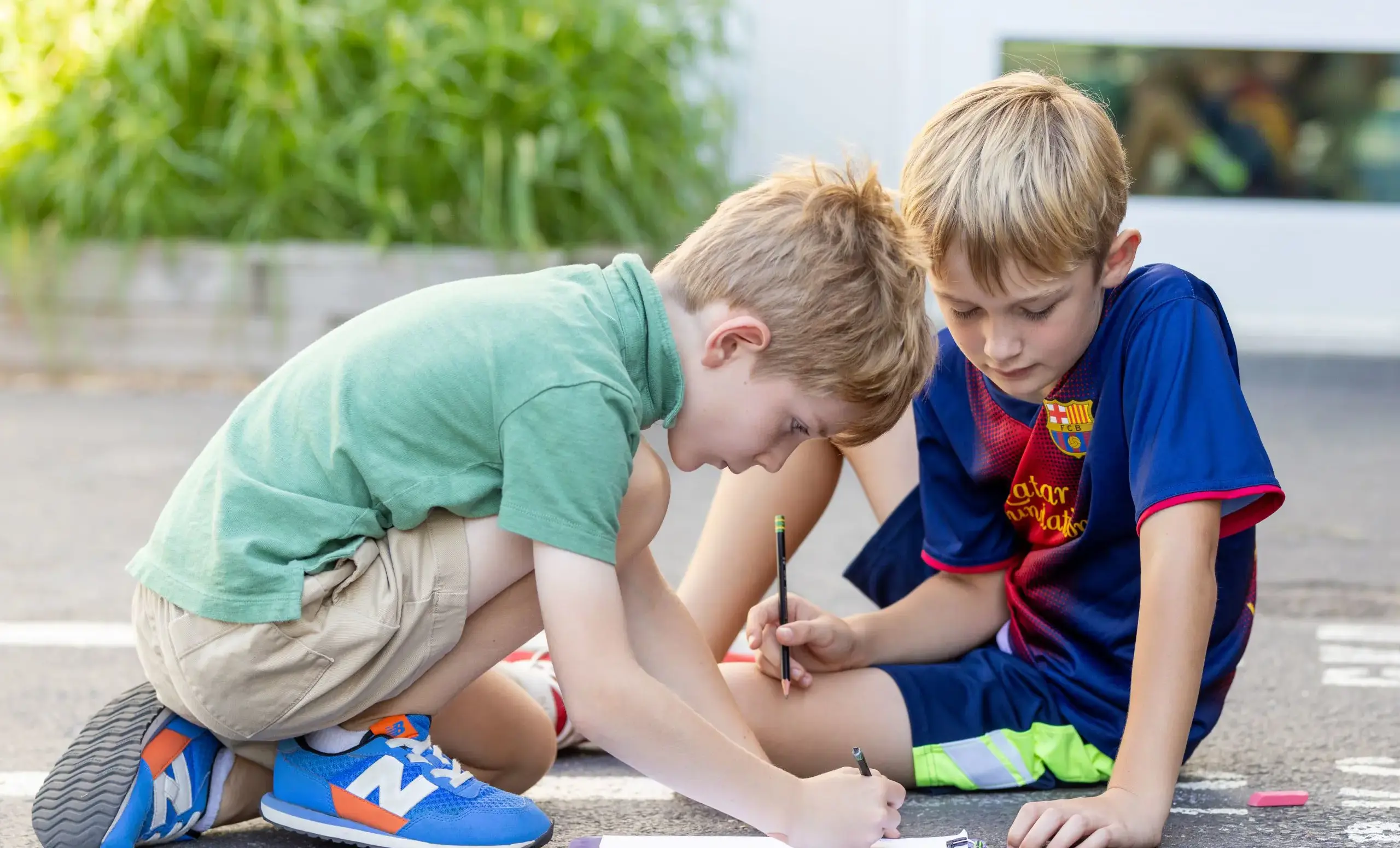 Two boys looking at a clipboard on the ground