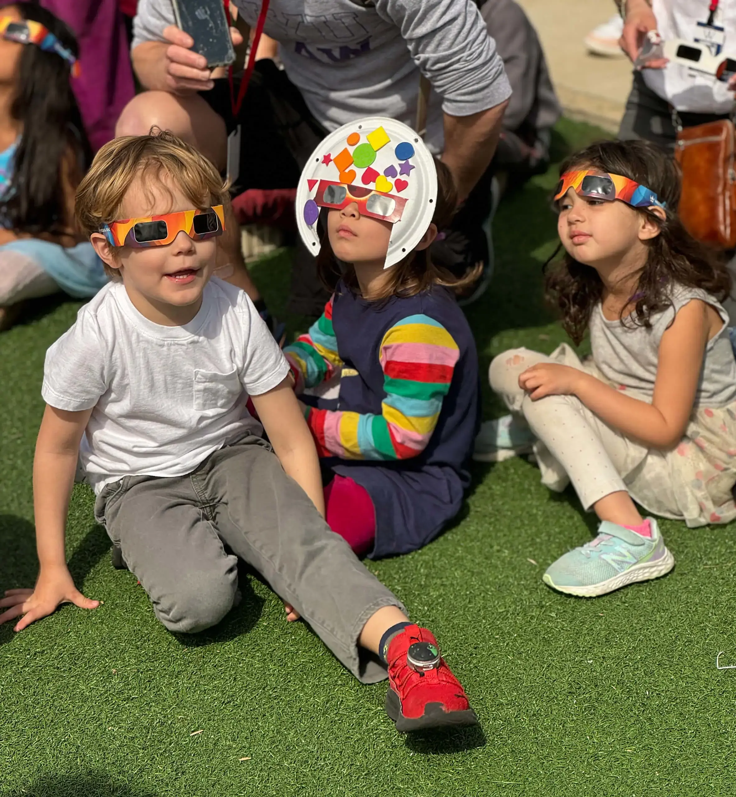 three children with glasses sitting on the ground